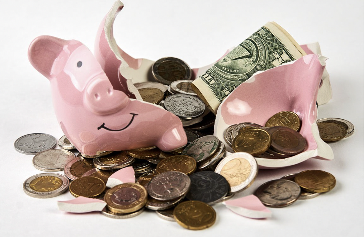 An image of a broken piggybank with coins and notes